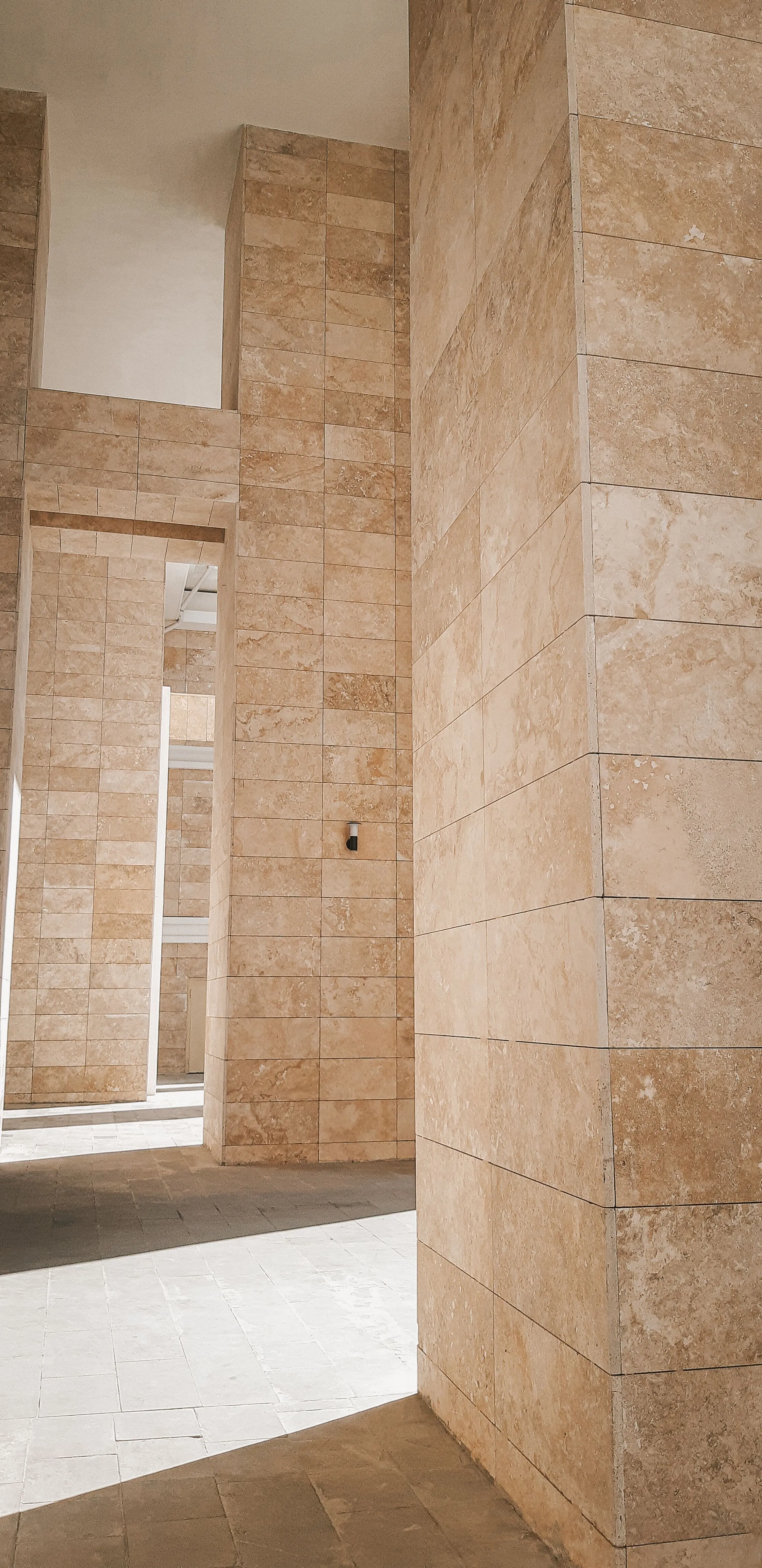 Tall stone columns inside a modern building, lit from above.